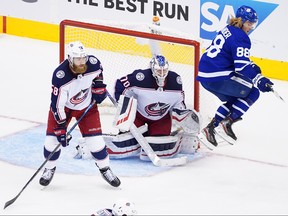 William Nylander of the Maple Leafs leaps out of the way of teammate's shot as Joonas Korpisalo and David Savard of the Columbus Blue Jackets defend in Game 5.