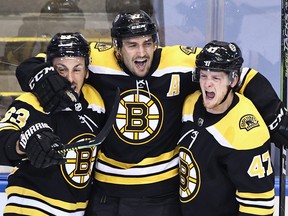 Patrice Bergeron  of the Boston Bruins (centre) scores at 1:13 of the second overtime against the Carolina Hurricanes during the second overtime period and is joined by Brad Marchand, left, and Torey Krug, right in Game 1 of the Eastern Conference First Round during the 2020 NHL Stanley Cup Playoffs at Scotiabank Arena on Aug. 12, 2020 in Toronto.