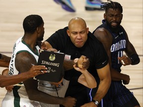 Marvin Williams, left, of the Milwaukee Bucks grabs the jersey of James Ennis III, right, of the Orlando Magic as referee Kevin Scott, second from left, and Bucks assistant coach Darvin Ham try to break up the scuffle in Game 3 of the Eastern Conference First Round.