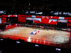 Players take a knee during the Canadian national anthem before the start of yesterday's game between the Raptors and Nets.