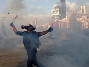 A demonstrator uses a tennis racket to return a tear gas canister to riot police, during a protest in Beirut, Lebanon, August 8, 2020.