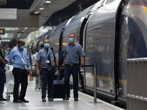 Passengers and staff wearing protective face masks arrive from Paris at Eurostar terminal at St Pancras station, as Britain imposes a 14-day quarantine on arrival from France from Saturday, following the outbreak of the coronavirus disease, in London, Britain Aug. 14, 2020.