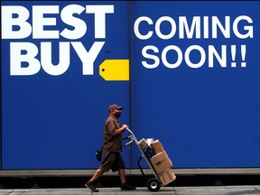 A delivery person passes by a sign for a new Best Buy store in New York City, Aug. 12, 2020.