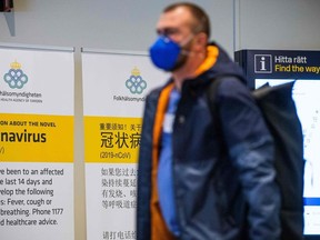 In this file photo taken on March 5, 2020 a passenger arriving in Stockholm's Arlanda airport is greeted by signs produced by the public health agency advising travelers what to do if they show symptoms of infection by the new coronavirus after arriving in Sweden.