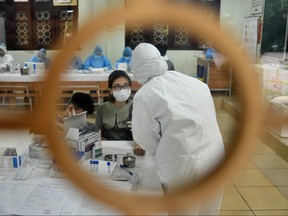 Health workers wearing protective suits collect a blood sample of a resident at a makeshift rapid testing centre in Hanoi on August 1, 2020, as Vietnam records a rise in cases of the COVID-19 coronavirus.