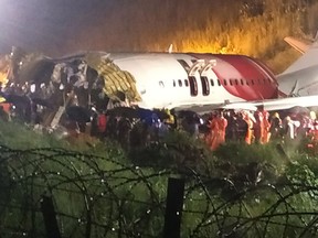 First responders gather around the wreckage of an Air India Express jet, which was carrying more than 190 passengers and crew from Dubai, after it crashed by overshooting the runway at Calicut International Airport in Karipur, Kerala, on August 7, 2020.
