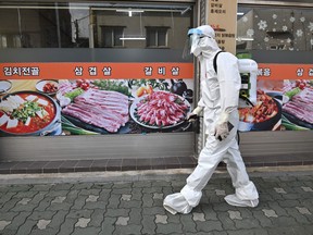 A health official wearing protective gear sprays disinfectant on the street near the Sarang Jeil Church, a new coronavirus infection cluster, in Seoul on Aug. 18, 2020.