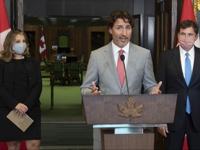 Standing in front of the House of Commons chamber Deputy Prime Minister and Minister of Finance Chrystia Freeland and President of the Queen’s Privy Council for Canada and Minister of Intergovernmental Affairs Dominic LeBlanc look on as Prime Minister Justin Trudeau speaks during a news conference on parliament hill in Ottawa, Tuesday, Aug. 18, 2020.
