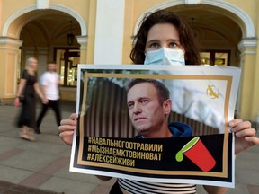 A woman holding a placard with an image of Alexei Navalny after he was rushed to intensive care in Siberia suffering from what his spokeswoman said was a suspected poisoning, in downtown Saint Petersburg, Thursday, Aug. 20, 2020.