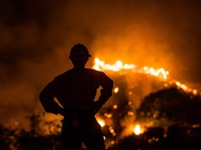 A firefighter watches the smoke and flames from the Ranch Fire in the hills in Azusa, California, on August 14, 2020.