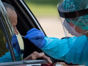 A healthcare worker uses a swab to test a man at a COVID-19 drive-in testing location in Houston, Aug. 18, 2020.