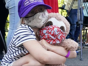 A child, wearing a mask, holds her teddy bear who is also wearing one, following the COVID-19 outbreak in New York's Central Park August 26, 2020.