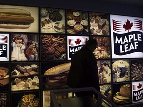 A Maple Leaf Foods employee walks past a Maple Leaf sign at the company's meat facility in Toronto on December 15, 2008.