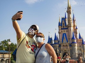 In this handout photo provided by Walt Disney World Resort, guests stop to take a selfie at Magic Kingdom Park on July 11, 2020 in Lake Buena Vista, Florida.