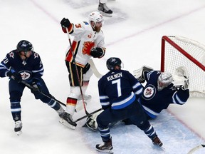 Calgary Flames’ Sam Bennett scores a goal on Jets goalie Connor Hellebuyck during Game 4 of their series last night. The Flames won, eliminating the Jets from the playoffs. Getty Images