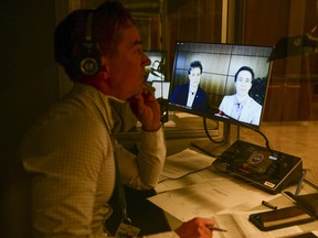 A translator works as WE Charity founders Marc Kielburger, screen left, and Craig Kielburger, screen right, appear as witnesses via videoconference during a House of Commons finance committee in the Wellington Building in Ottawa on Tuesday, July 28, 2020.