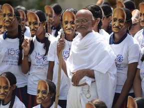School children wear masks as a man dressed like Mahatma Gandhi stands at a school in Chennai on September 30, 2019, ahead of Gandhi's 150th birth anniversary.