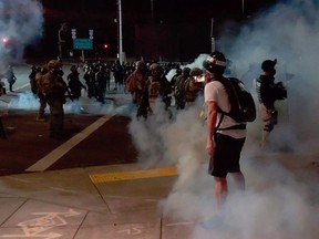 A member of the media stands amid tear gas used by police officers to clear protesters near an Immigration and Customs Enforcement centre in Portland, Oregon, U.S., August 19, 2020, in this still image from a video obtained from social media. TWITTER/DAVE_BLAZER / INSTAGRAM/AARON2543 /via REUTERS THIS IMAGE HAS BEEN SUPPLIED BY A THIRD PARTY. MANDATORY CREDIT. NO RESALES. NO ARCHIVES. ORG XMIT: POR001