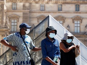 People wearing protective masks walk near the Louvre Museum as France reinforces mask-wearing as part of efforts to curb a resurgence of the coronavirus disease (COVID-19) across the country, in Paris, France August 6, 2020.