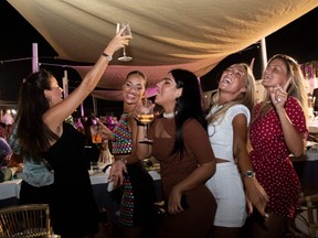 Women dance at an outdoor restaurant on a beach in Fregene, near Rome, on August 14, 2020.