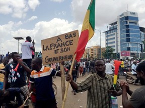 Opposition supporters react to the news of a possible mutiny of soldiers in the military base in Kati, outside the capital Bamako, at Independence Square in Bamako, Mali August 18, 2020.