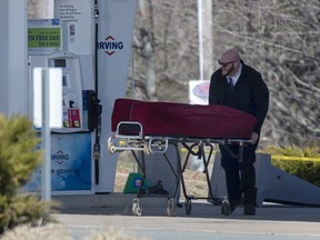A worker with the medical examiner's office removes the body of Gabriel Wortman from a gas bar in Enfield, N.S. on Sunday, April 19, 2020.