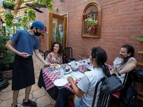 A server at Mamma Martino's Restaurant serves customers after indoor dining restaurants, gyms and cinemas re-open under Phase 3 rules from COVID-19 restrictions in Toronto, July 31, 2020.