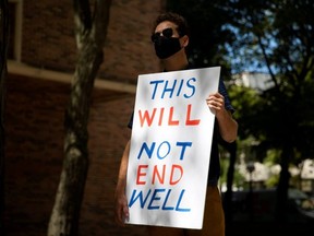 A faculty member holds a sign as students and faculty protest in-person classes for fall semester amid the COVID-19 pandemic, outside Fleming Administrative Building at the University of Michigan campus in Ann Arbor, Mich., Aug. 19, 2020.