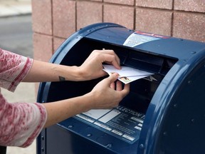 An individual deposits letters into a U.S. Postal Service (USPS) collection mailbox in Philadelphia, Pennsylvania, U.S., August 14, 2020.