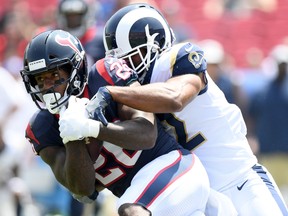 Lamar Miller of the Houston Texans is tackled by Brian Peters of the Los Angeles Rams during a preseason game at Los Angeles Memorial Coliseum on August 25, 2018 in Los Angeles, California.
