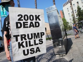 A protester holds a sign reading '200K Dead Trump Kills USA' at a march against 'Death, Lies and Fascism' in Los Angeles, Monday, Sept. 21, 2020.