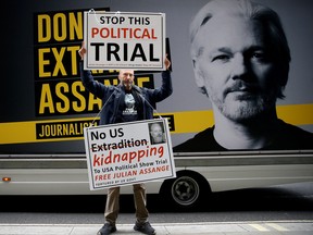 A protestor holds signs outside the Old Bailey, the Central Criminal Court ahead of a hearing to decide whether Assange should be extradited to the United States, in London, Britain Sept. 8, 2020.