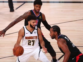 Denver Nuggets guard Jamal Murray, left, handles the ball while Los Angeles Clippers guard Paul George and forward Kawhi Leonard, right, during the first half in game seven of the second round of the 2020 NBA Playoffs at ESPN Wide World of Sports Complex, Sept. 15, 2020.