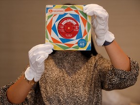 A member of staff poses for a photograph with a first pressing of the record "Love Me Do" signed by all four Beatles at Sotheby's auction house ahead of their "Beatles for Sale" auction in London September 25, 2020.