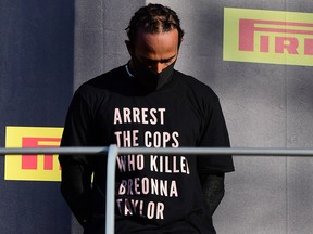 Lewis Hamilton wears a shirt in reference to Breonna Taylor on the podium as he celebrates after winning the Tuscan Grand Prix.