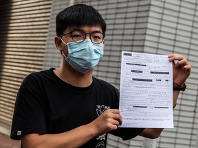 Pro-democracy activist Joshua Wong speaks to the media while holding up a bail document after leaving Central police station in Hong Kong on September 24, 2020.