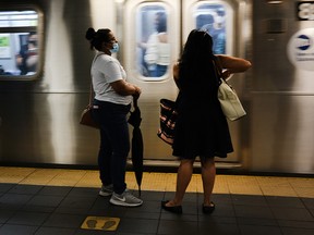People, most with face masks, wait on a ride the subway on September 10, 2020 in New York City.