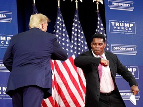 President Donald Trump elbow-bumps retired NFL player Herschel Walker before delivering remarks on Black Economic Empowerment during an event at the Cobb Galleria Centre in Atlanta September 25, 2020.