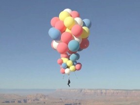 Extreme performer David Blaine hangs with a parachute under a cluster of balloons during a stunt to fly thousands of feet into the air in a still image from video taken over Page, Arizona, September 2, 2020.