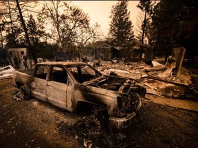 A burned vehicle is seen next next to a house reduced to ashes by the Glass Fire in Napa Valley, Calif, Monday, Sept. 28, 2020.