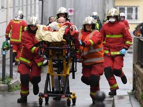 French firefighters push a gurney carrying an injured person near the former offices of the French satirical magazine Charlie Hebdo following an alleged attack by a man wielding a machete in Paris on Sept. 25, 2020.