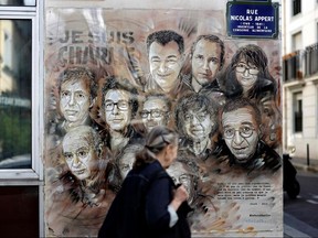 A woman walks past a painting by French street artist and painter Christian Guemy, known as C215, in tribute to members of Charlie Hebdo newspaper who were killed by jihadist gunmen in January 2015, in Paris, on August 31, 2020.