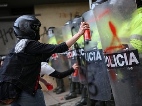 People spray paint on police riot shields as they protest outside a police station after a man died from being repeatedly shocked with a stun gun by officers in Bogota, Colombia September 10, 2020.