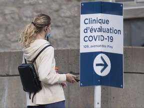 A woman wears a face mask as she walks by a sign for a COVID-19 testing clinic in Montreal, Saturday, Sept. 5, 2020, as the COVID-19 pandemic continues in Canada and around the world.