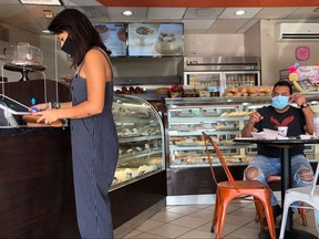 In this file photo, customers are seen inside a bakery as Miami-Dade county allows indoor servicing in restaurants after easing some lockdown measures put in place during the coronavirus outbreak, in Miami, Florida, Aug. 31, 2020.