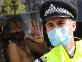A climate activist shows her hand as she sits inside a police van after being detained during an Extinction Rebellion protest in London, Sept. 10, 2020.