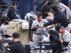 San Francisco Giants players and coaches wait in the dugout before a scheduled game against the Padres at Petco Park on September 11, 2020 in San Diego.
