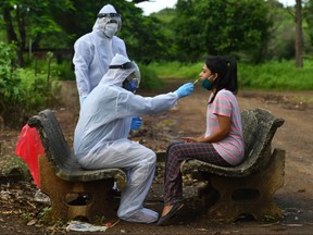 Medical staff wearing personal protective equipment take a nasal swab sample from a woman during a screening outside a quarantine centre, in Nashik on September 13, 2020.