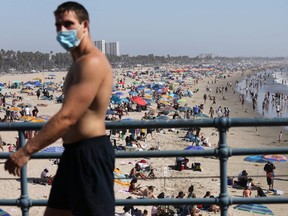 A man wears a face covering at the pier on the first day of the Labor Day weekend amid a heatwave in Santa Monica, Calif., Sunday, Sept. 5, 2020.