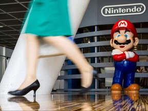 A woman walks past a figure of "Mario," a character in Nintendo's "Mario Bros." video games, at a Nintendo centre in Tokyo, July 29, 2015.